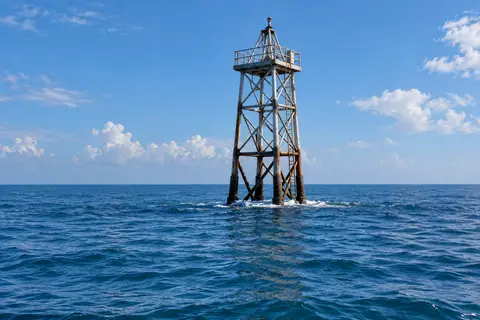 A channel marker tower standing in open Gulf water