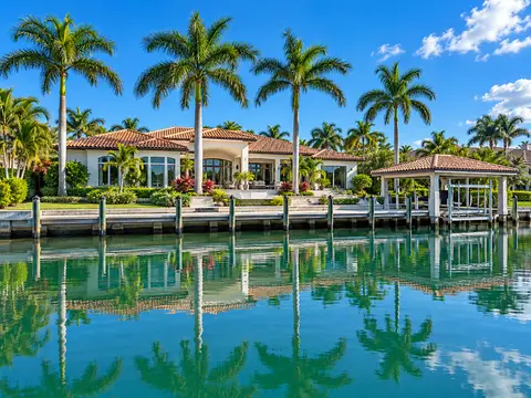 White stucco waterfront home with terracotta roof and dock